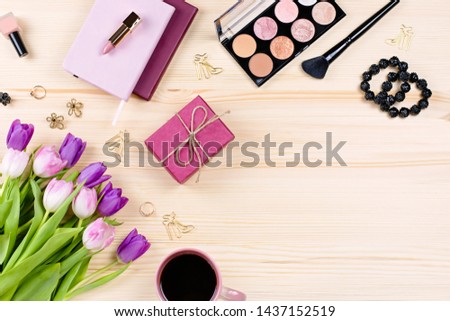 Feminine desk with stationery, notebooks, fashion accessories, flowers and make up products. Woman accessories lay out