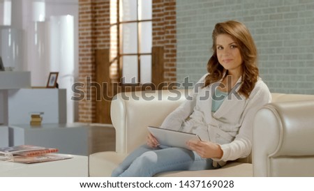Young woman enjoying work on tablet, satisfied with app of smart home control
