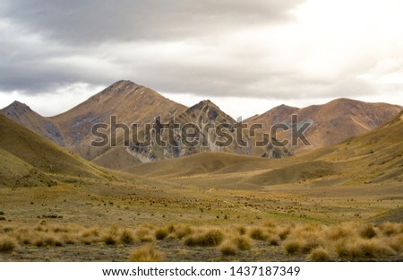 Mountain range in New Zealand, dry grass, meadow, cloudy day, landscape picture, nature. 