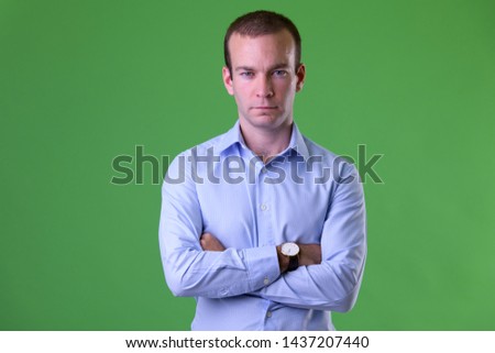 Portrait of businessman with arms crossed against green background
