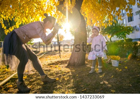 Girl with mom in autumn. Mom takes a picture of her daughter. Autumn photo shoot child. Mother photographer. Mother with her little daughter in the autumn park on a walk. 