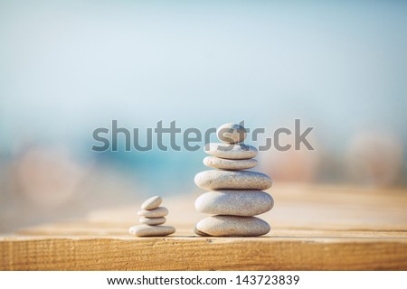 zen stones on wooden banch on the beach near sea. Outdoor. en style path on vintage wood table in relaxing wellness holistic spa for relaxation and good health rejuvenation Royalty-Free Stock Photo #143723839