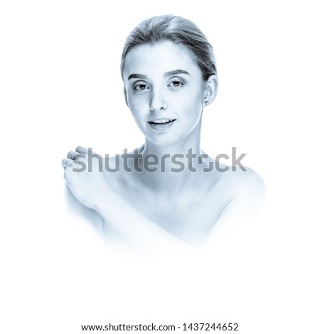 Portrait of attractive woman touching shoulder, black and white image in high key style with blue toning and soft vignetting