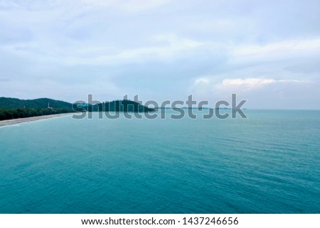 Island seen from areial view with emerald, green and blue colors clouds and the ocean for backgrounds, vacation catalogs, patterns and wallpaper