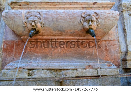 an ancient fountain designed for drinking water with reliefs in the form of a faces
