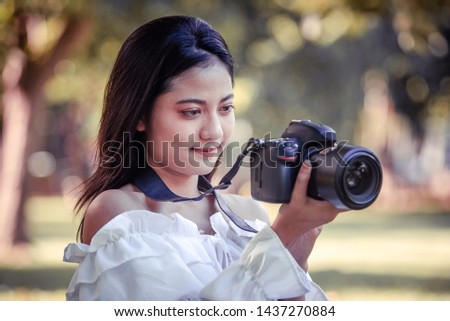 photographer woman in park summer, beautiful girl taking a picture by the camera, she is a professional traveler, hipster woman in costume fashion, vintage style, photo portrait concept. Asian