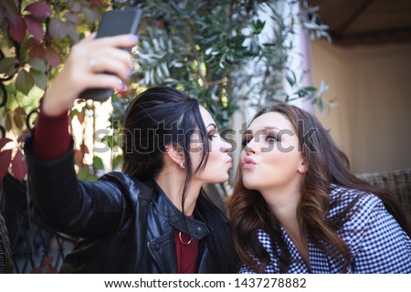 Two beautiful women taking selfie in cafe, daytime