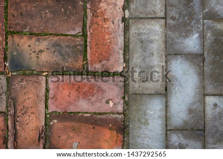 Old and new - Tip viiew of red bricks and gray cement blocks flooring texture pattern detail - green moss in the seams