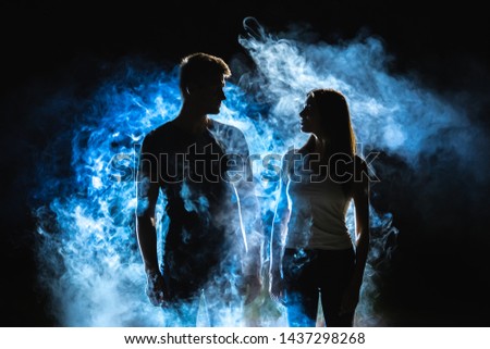 The man and woman standing near the smoke in the dark
