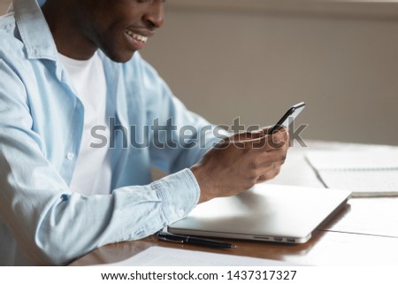 Cropped image close up view african guy sit at table using smart phone enjoy new funny application, communicating online, browse websites feeling satisfied, modern wireless tech wi fi user concept