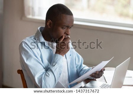 African guy cover mouth with hand holds letter reading shocking unexpected news from bank about loan debt financial problems feels disappointed, troubled with bad notice or failed test results concept Royalty-Free Stock Photo #1437317672
