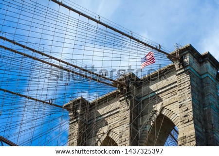 Brooklyn Bridge photo with United States of America flag in the sky between steel cables