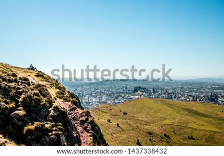A young couple rest while admiring the view over the city of Edinburgh on a beautiful sunny day.  Great shot for promotional material, space for logos and text.