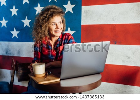 Nice picture of young  woman  in casual style , with curly hair sitting in a coffee shop and working on laptop.