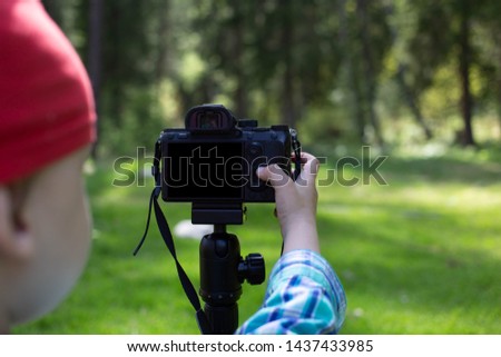 3 year old boy uses digital camera outdoors