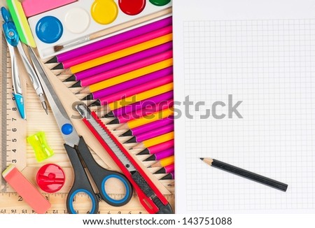Colorful pencils with notepad and school accessories over wooden surface