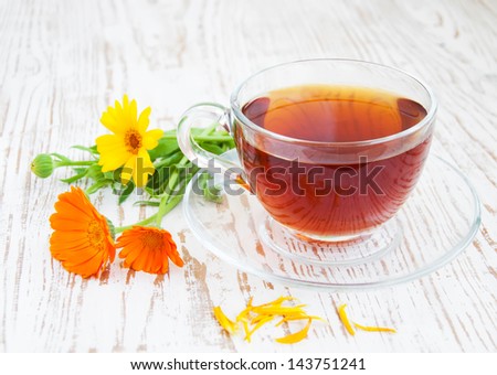 Tea cup with calendula flowers on a wooden background