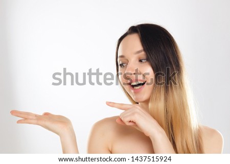 Portrait of Beautiful Surprised Woman. Cute Lady with Long Ombre Hair Pointing to the Side. Female Showing your Product. Close Up Isolated on White Background