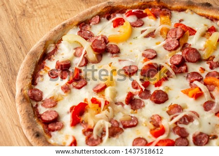 Tasty Italian pizza Mexicano on wooden  background. Top view of hot pizza with chili pepper , hot sausages, onion, tomatoes and cheese. Flat lay.