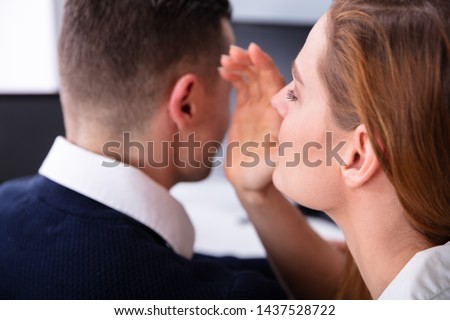 Close-up Of Businesswoman Whispering Into Male Partner's Ear Royalty-Free Stock Photo #1437528722