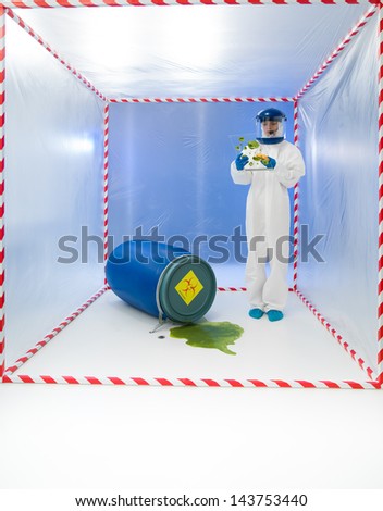 female specialist standing in a cube surrounded with red and white tape, with a blue barrel near her labeled as biohazard