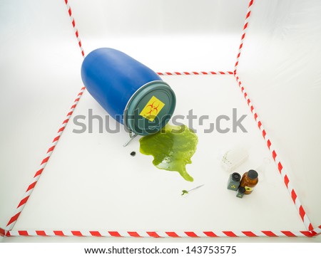 upper view of toxic waste spilling from a blue barrel in a white cube surrounded with red and white tape