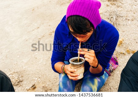 Portrait of Young latin woman drinking traditional Argentinian yerba mate tea with tablet.