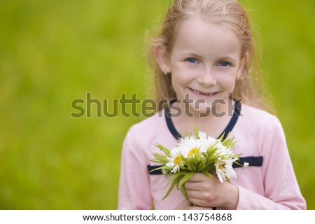 portrait of little girl holding flowers bunch and smiling outside. horizontal shot