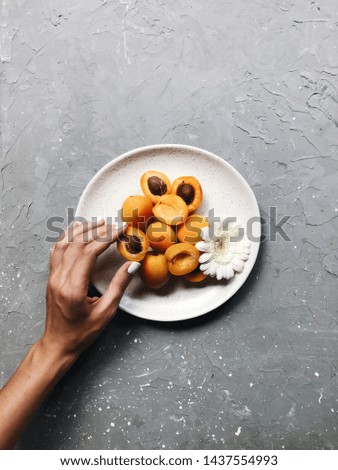 A girl is holding a plate with apricots and flowers.