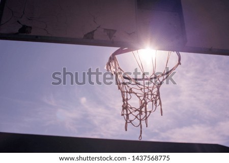 Basketball hoop shot from behind with sun shining through rim