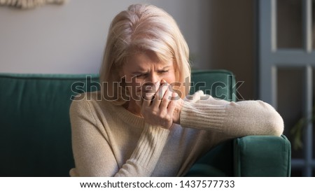 Sad stressed old middle aged woman widow mourning crying alone sit on couch at home, upset desperate senior mature elder grandma grieving weeping suffering from anxiety grief sorrow disease concept Royalty-Free Stock Photo #1437577733