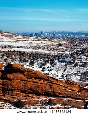 Snowy winter landscape in Denver Colorado with red rocks, valley, and a city in the background