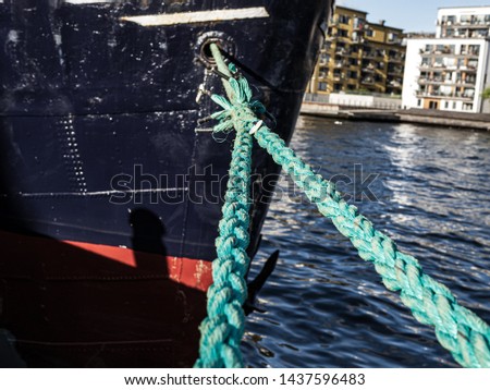 Bright green thick ropes tied tightly for a  secure harbor docking. The boat is docked in the Swedish capital Stockholm.
