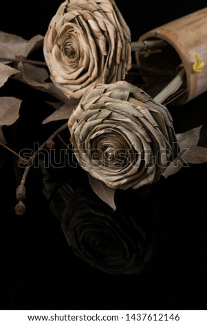 Roses from dried pandan leaves on a black background.