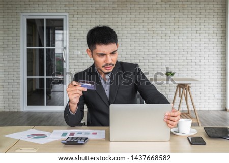 A young Asian business man looking at laptop and frustrated with online purchasing with credit card.