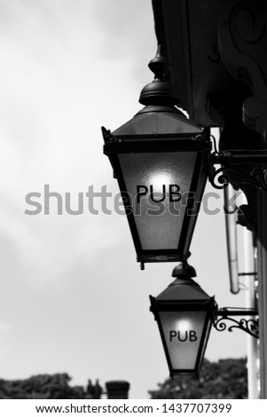 Monochrome pub sign on retro style lamp outside public house on period building
