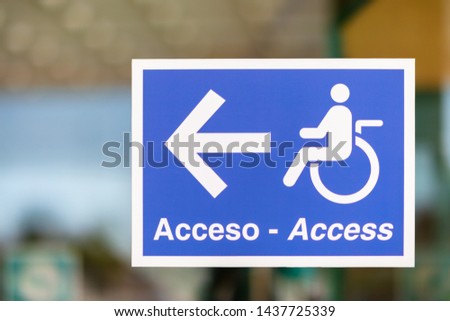 A sign on a glass screen in the entrance area at a hospital in Spain. Disabled people and wheelchair users see where they find a suitable door in the building.