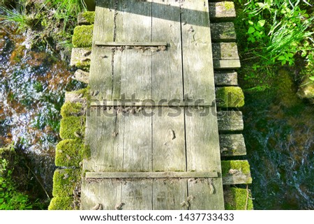 Little aged wooden bridge over a stream from bird's perspective