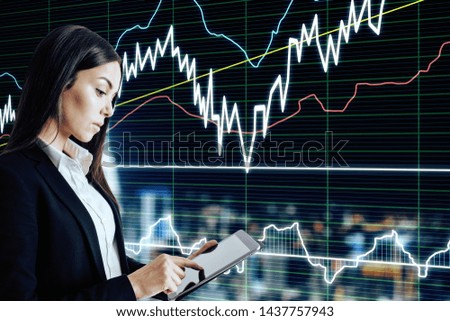 Attractive young european businesswoman using tablet with forex chart interface on blurry night city background. Invest and technology concept. Double exposure 