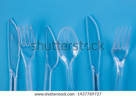 plastic forks and knifes on blue background. copy space