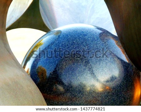 decorative shiny polished black granite ball with strong reflections and brushed light color curving steel elements around. abstract closeup detail view. art and abstract concept. copy space.