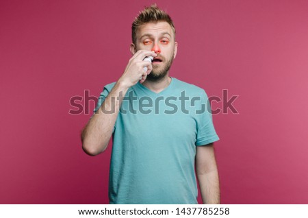 studio picture from a young man uses nose spray. Sick guy isolated has runny nose. man makes a cure for the common cold