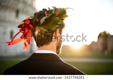 Young graduate boy with the triumphal laurel wreath on his head seen from behind. Royalty-Free Stock Photo #1437798281