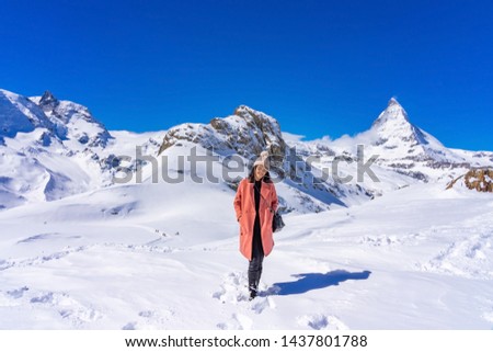 Young woman tourist enjoying with snow mountain Matterhorn peak background in winter day, Zermatt, Switzerland.