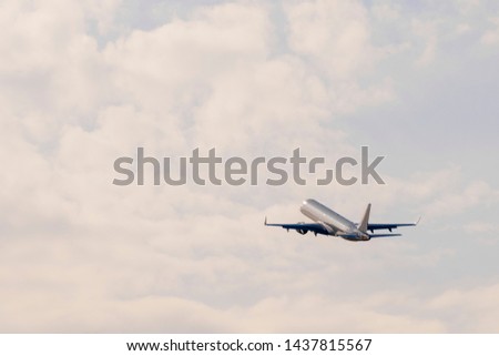 Airplane goes towards the clouds at sunset after take off