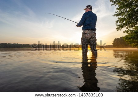 Angler catching the fish during sunrise
 Royalty-Free Stock Photo #1437835100