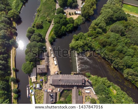Aerial footage of the The Made in Leeds Festival located at the Thwaite Mills along the side of the Leeds Canal showing the water and waterfall, on a sunny day