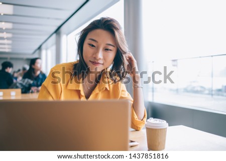 Positive female freelancer downloading media files during distance job with startup project using high speed internet connection on netbook, successful student preparing course work presentation Royalty-Free Stock Photo #1437851816