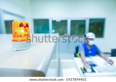 Male science researcher in protective uniform works in x-ray laboratory, ionizing radiation hazard symbol on foreground. Selective focus. Royalty-Free Stock Photo #1437894401