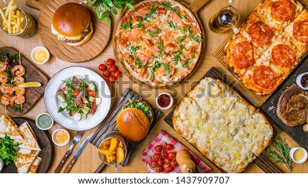 assorted foodset on table. Pizza Quattro formaggi on the Rome dough, pizza with parma ham, burges, shrimps, steak ribeye, french fries top view food. Royalty-Free Stock Photo #1437909707